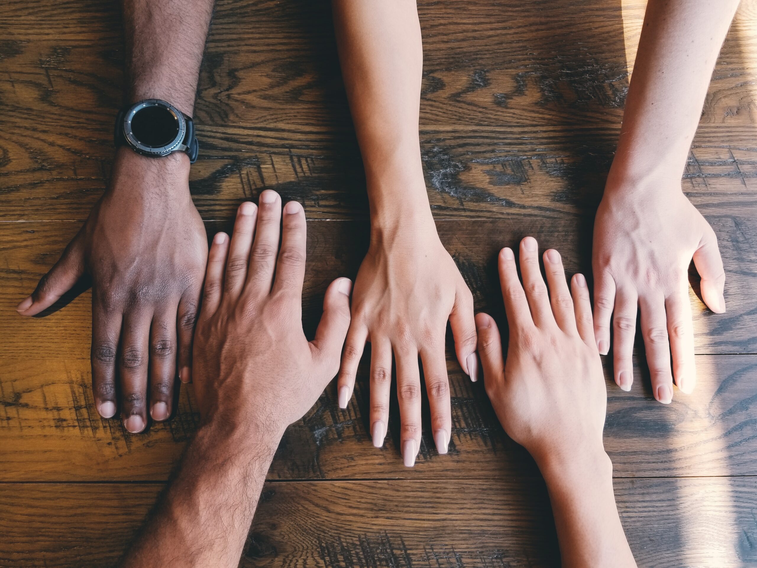 Five Human Hands On Brown Surface Scaled 